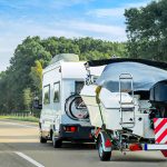 Caravan and trailer for motor boats on road in Switzerland