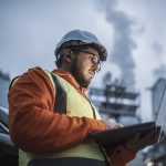 Serious handsome engineer using a laptop while working in the oil and gas industry.