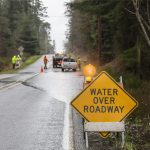 Emergency workers placing warning signs on flooded road