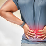 Shot of an unrecognizable man standing alone outside and suffering from backache during his run