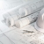 Doomed Before the Pour: When Pre-Construction Plans Fail Hard hat and compass on architectural blueprints and construction technology and future industry