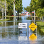 Blame the Rain or the Brains? Decoding Liability in Stormwater Flood Claims Road closed because of flooding danger with warning signs blocking driving of cars. Hurricane Milton aftermath in Punta Gorda, Florida