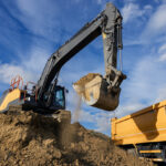 Crack the Case: Is Nearby Construction Really Behind That Property Damage? Excavator Loading Soil into Dump Truck at Construction Site